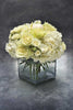 Low flower arrangement of all white flowers with roses and hydrangeas