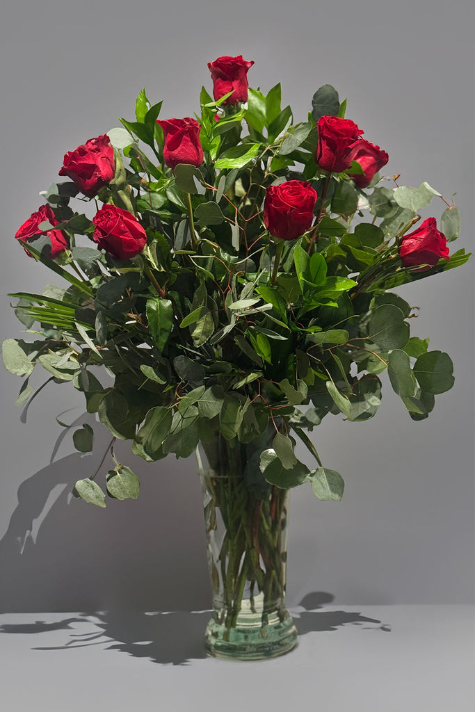 Long stemmed classic roses arranged in a vase with greenery 