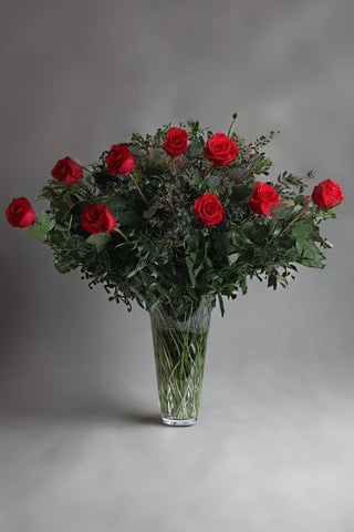 Long stemmed classic roses arranged in a vase with greenery 