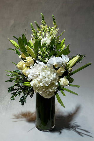 Elevated white and green arrangement with seasonal flowers in a glass vase called Everly