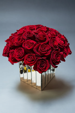 60 Red Roses arranged in a cube vase with mirror reflections on the outside 