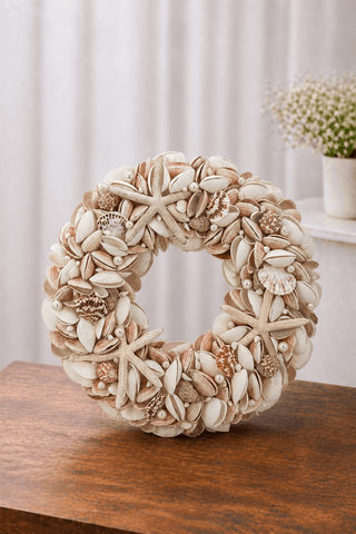 Pink Seashell wreath with starfish, pearls, and assorted natural shells displayed on a wooden table in a soft neutral setting.