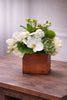 Penelope floral arrangement in a rustic wooden cube with white phalaenopsis orchids, hydrangea, succulents, green trick dianthus, and seasonal blooms.