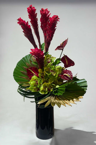 Colorful vibrant colorful arrangement of tropical flowers arranged in a black vase
