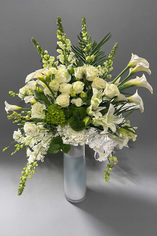 Tall luxury white flower arrangement with orchids, roses, lilies, and calla lilies in a frosted glass vase, approximately 45 inches tall.