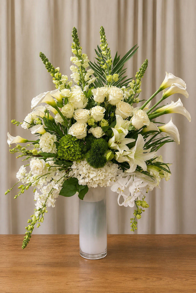 Tall luxury white flower arrangement with orchids, roses, lilies, and calla lilies in a frosted glass vase, approximately 45 inches tall.